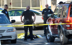 A group of Antioch police officers  stand around  the body of a 32-year-old male after a drive-by shooting in the parking lot outside the 24 Hour Fitness
